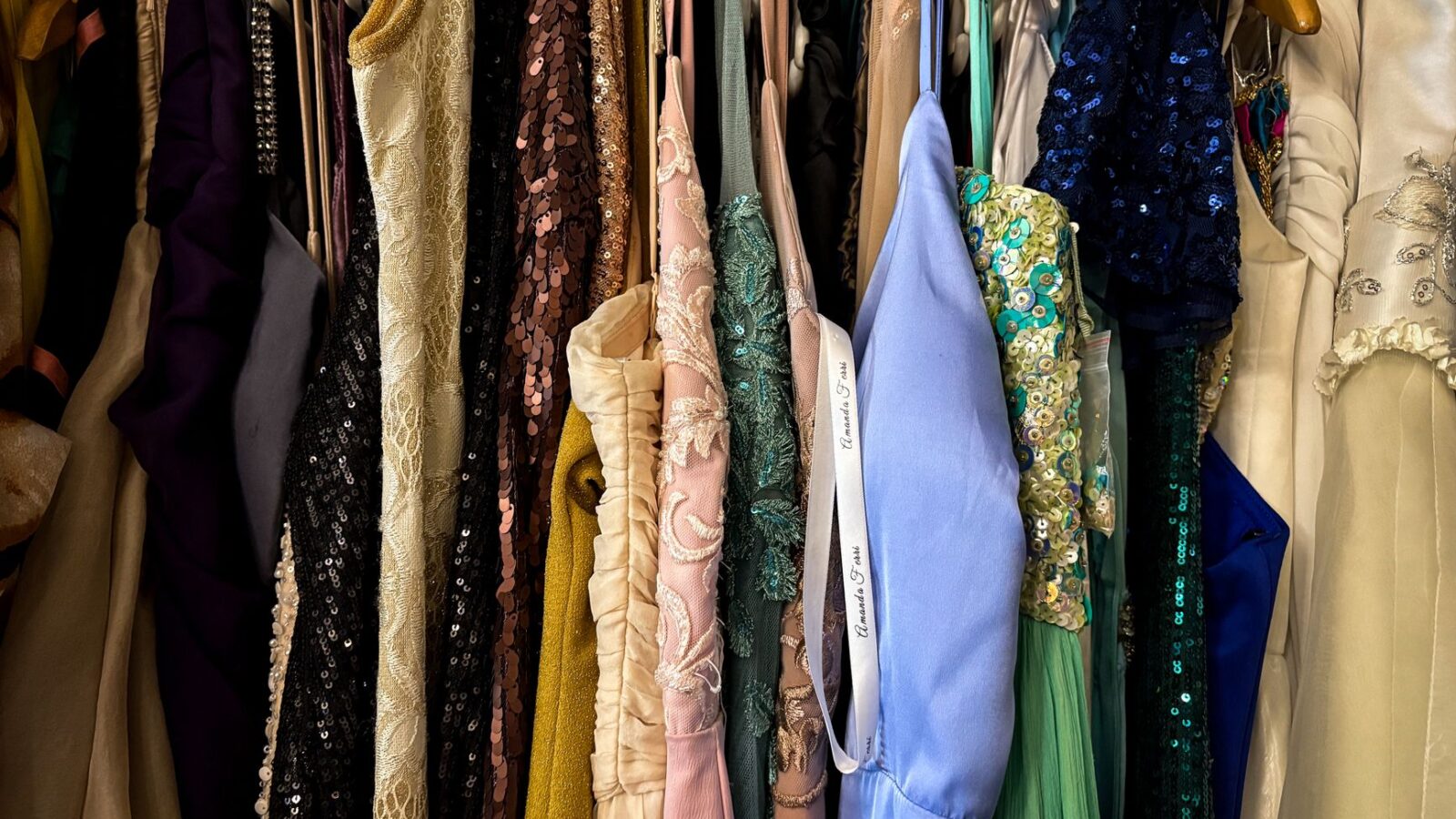 Rack of secondhand children's clothing on wooden hangers at a thrift store