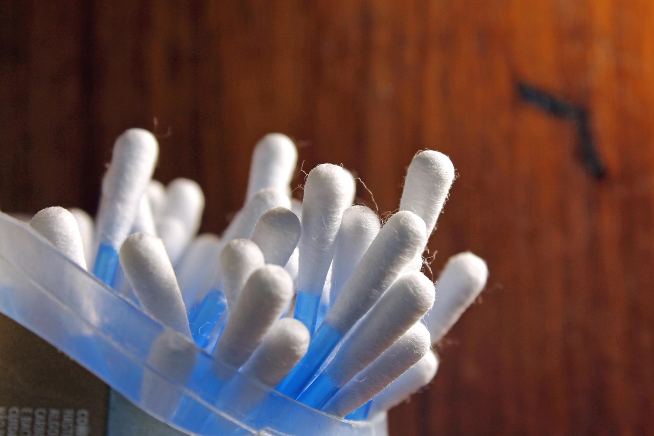 Folded cotton cleaning rags in white, blue, yellow, and red stacked in an open woven basket on a kitchen counter