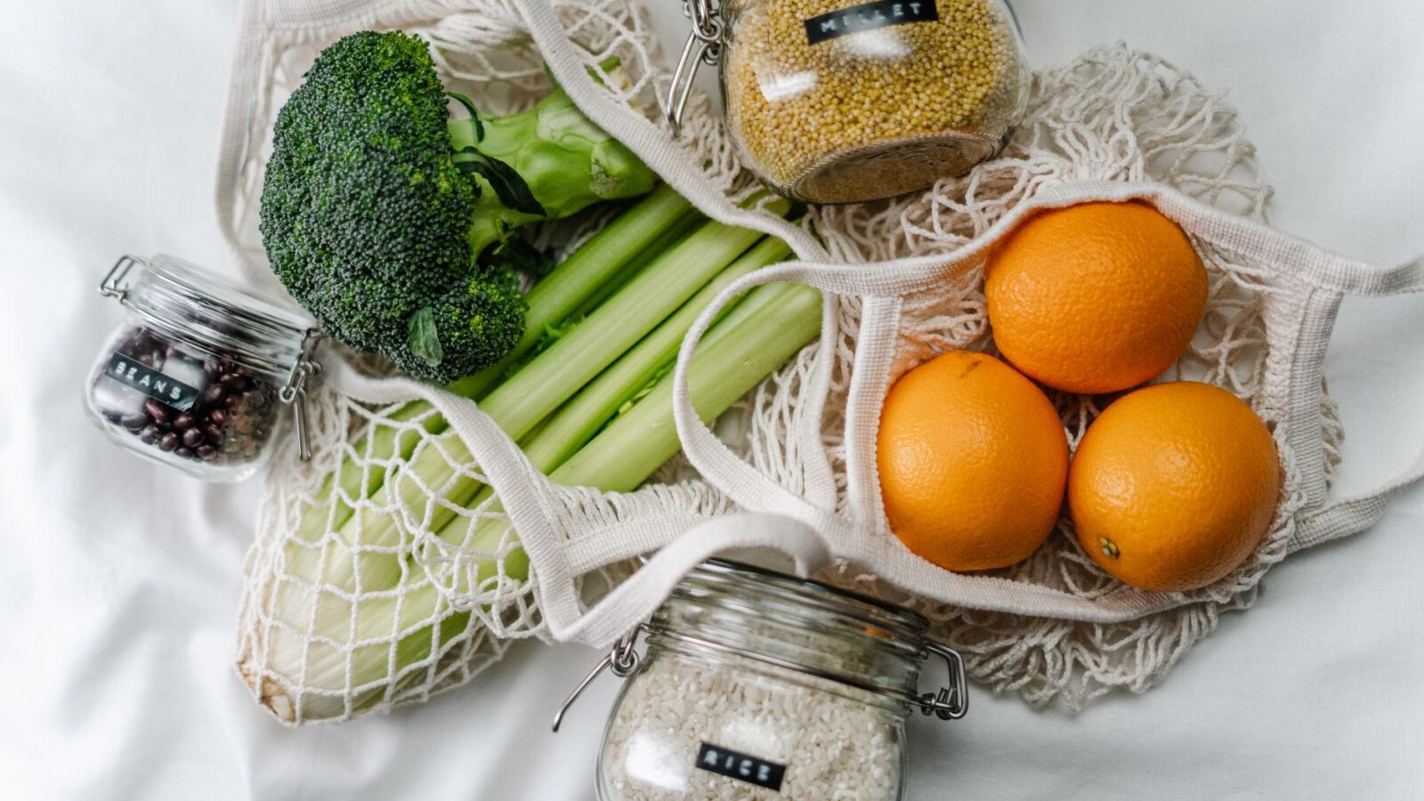Wooden countertop with a chef's knife, glass storage jars, cotton produce bags, and a kitchen scale.
