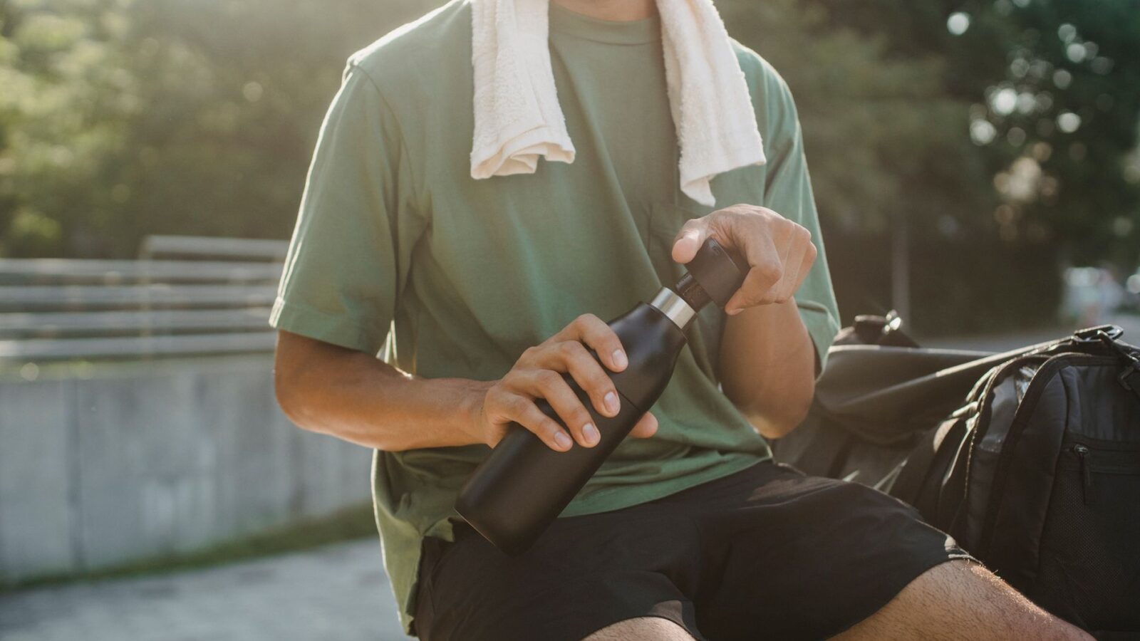 A collapsible metal water bottle beside a coffee cup and cotton napkin on an airport terminal seat